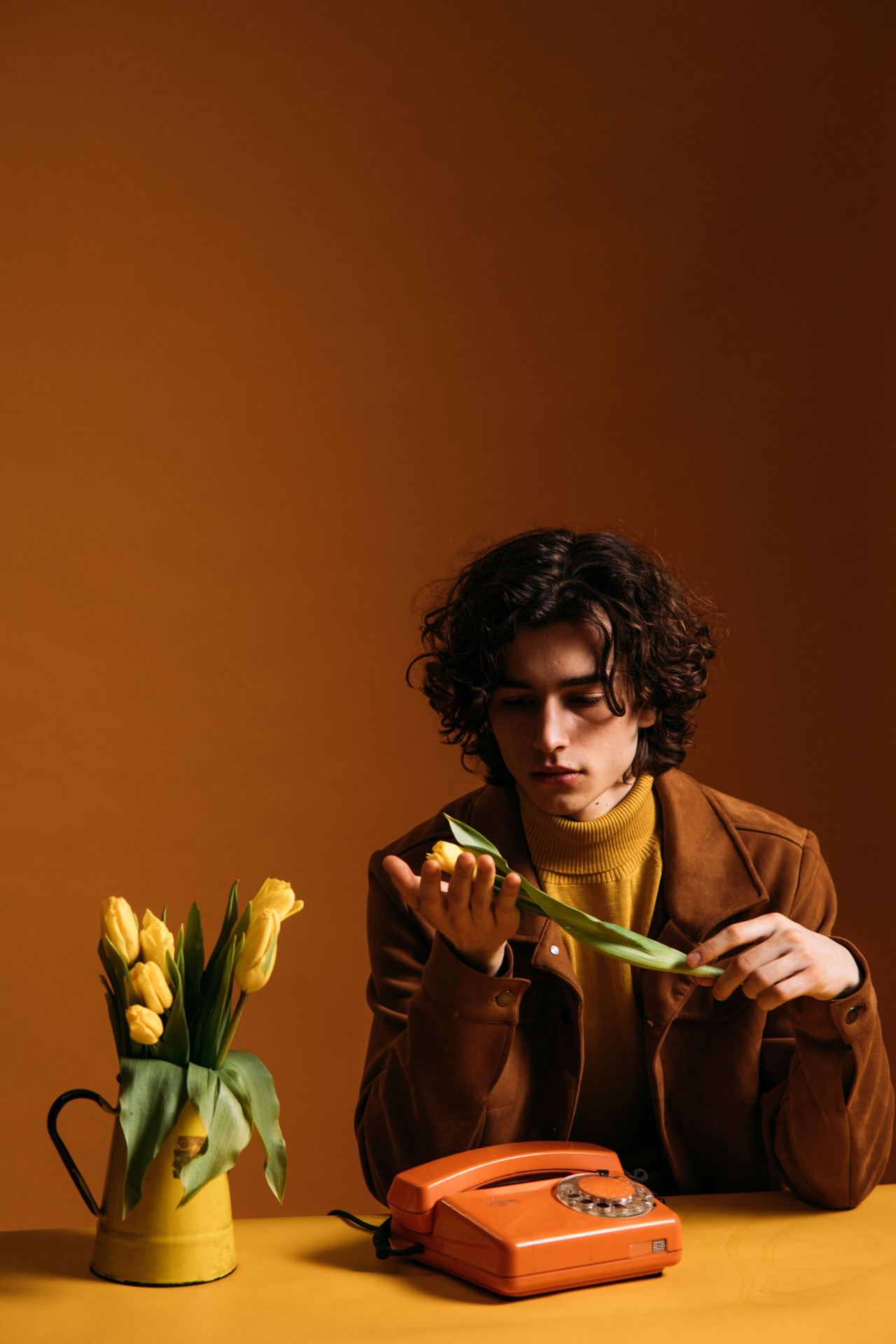 A young man with curly hair at a yellow table